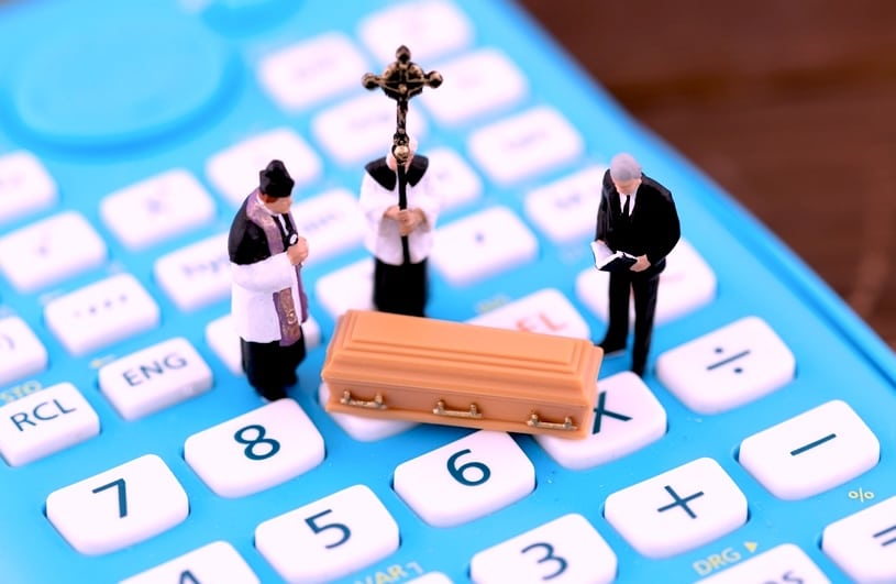 A blue calculator with miniature figures depicting a funeral