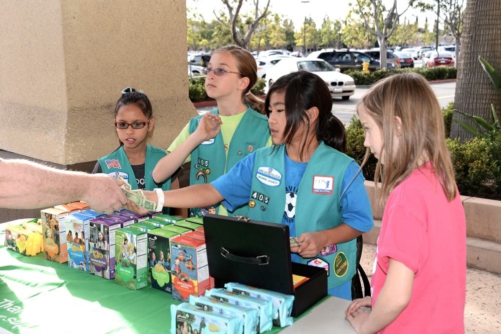 Four young Girl Scouts selling boxes of cookies outdoor