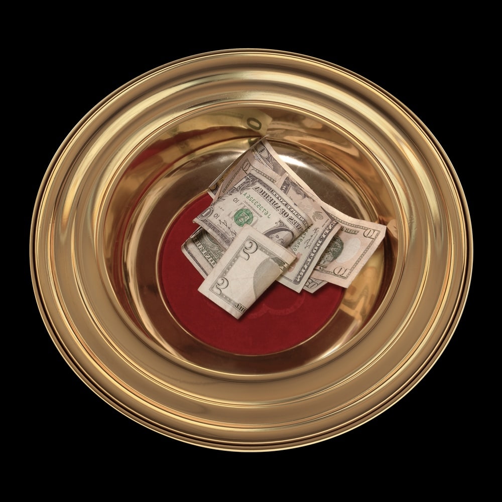 Money inside a golden donation bowl for a church