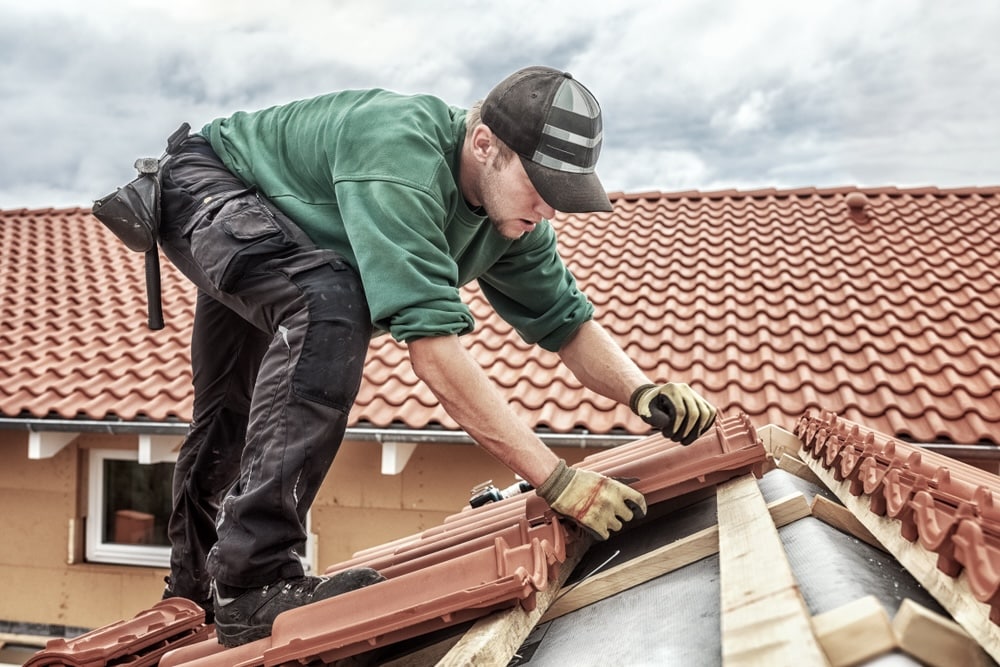 Construction worker wearing green shirt working on a roof replacement 