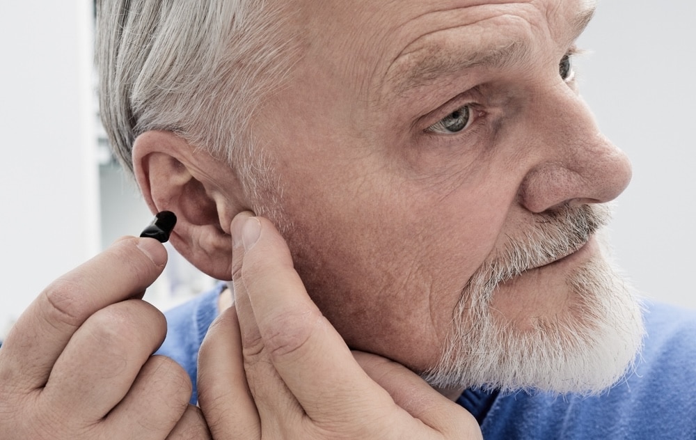 Older man putting in a hearing aid