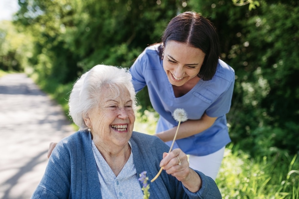 Nurse smiling with an elderly patient in the garden of assisted living home