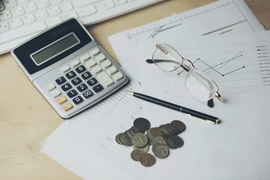 A table with eyeglasses, a calculator, coins, and a pen. Are eyeglasses tax deductible.