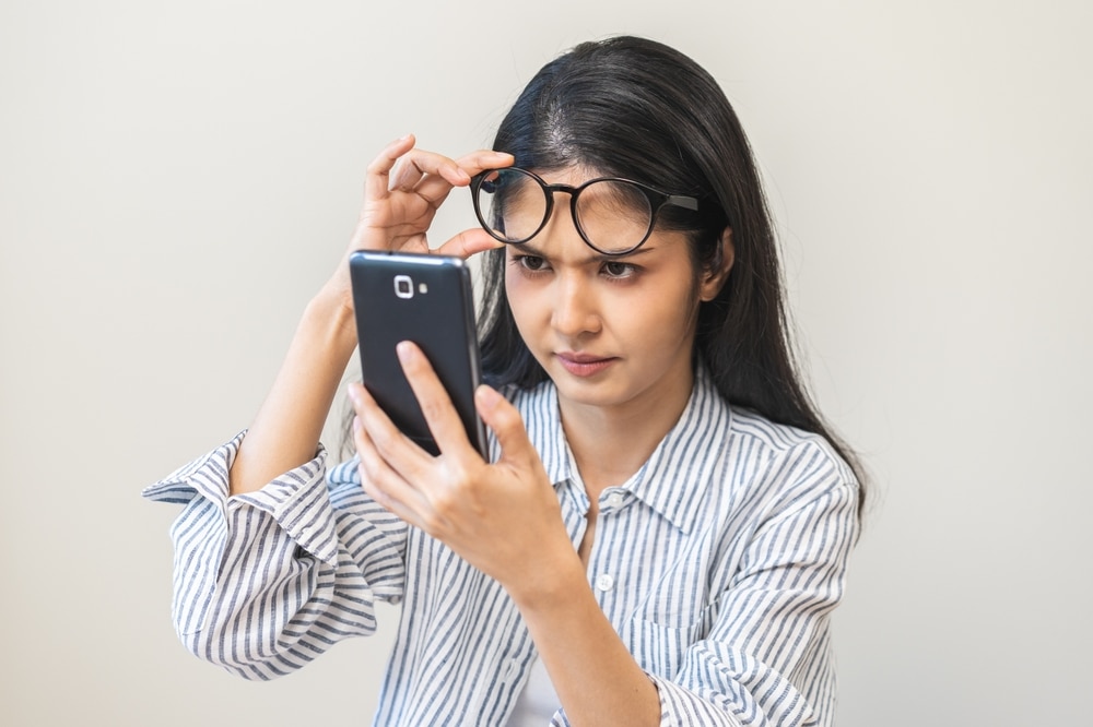 A woman wearing eyeglasses while searching for her phone if eyeglasses are tax-deductible.