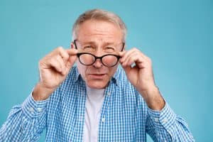 A senior citizen is holding his eyeglasses wondering if it is tax deductible.