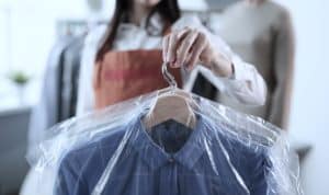 Staff at the dry cleaners holding newly cleaned clothes